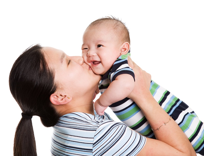 An image of a mother holding and kissing a baby